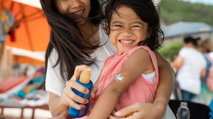 Mom putting sunscreen on child skin as recommended by dermatologist