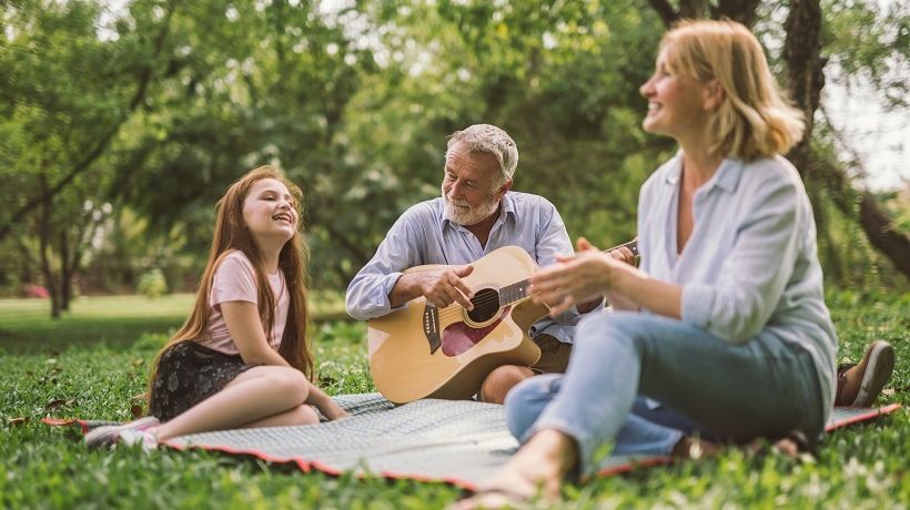 Family playing guitar outside with healthy ear, nose and throat