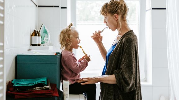 Daughter brushing teeth with pregnant mother