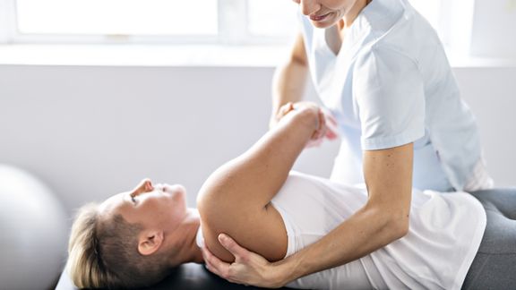 Patient stretching with physical therapist